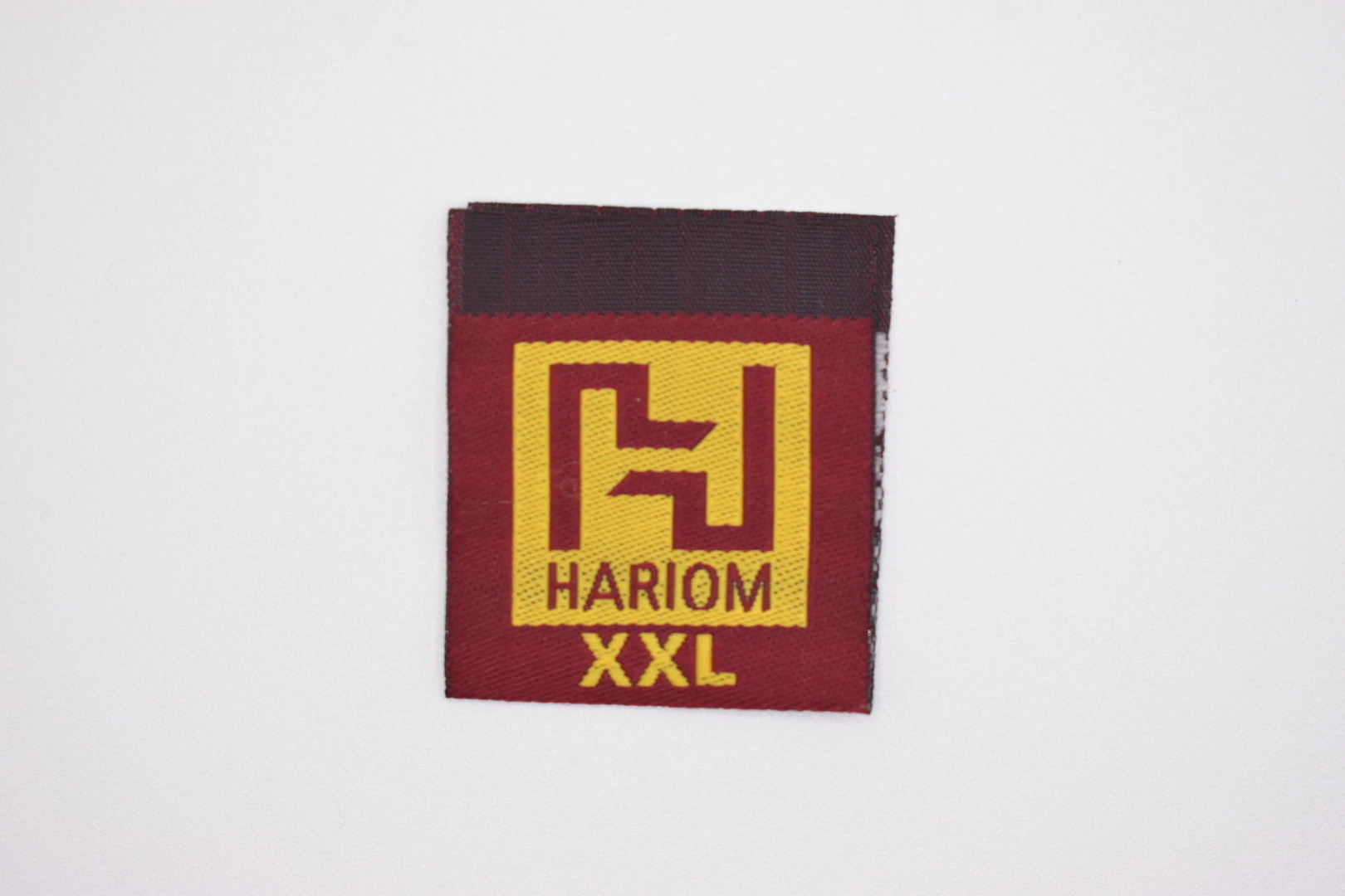 Hariom centre-fold woven brand label — front view, premium woven clothing label sample