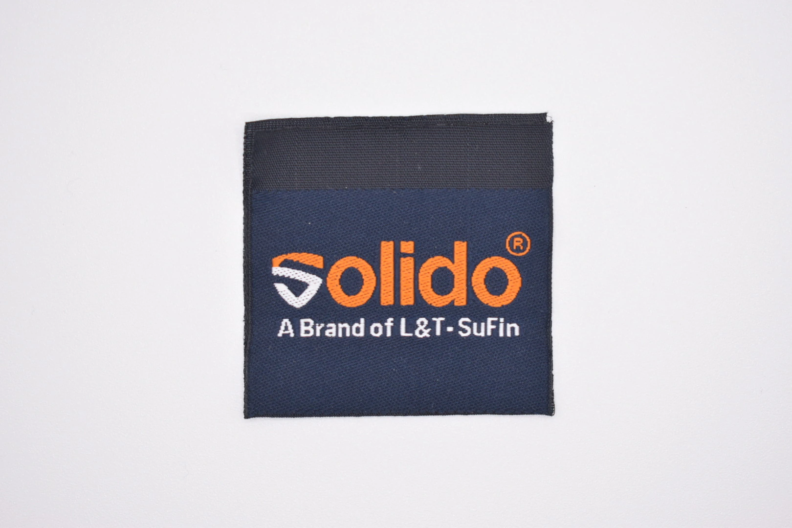 Solido centre-fold woven brand label — front view, premium woven clothing label sample