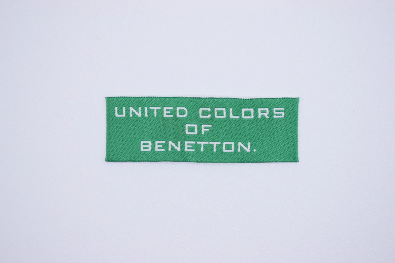 United Color end-fold woven brand label — front view, custom clothing label sample