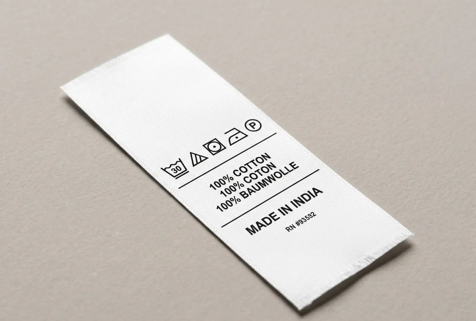 White taffeta care label printed with multilingual fibre content (English, French, German), care symbols, Made in India and RN number